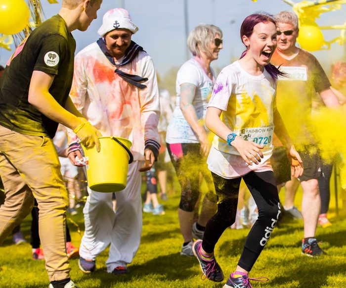 Child and group of adults running at the Rainbow Run.